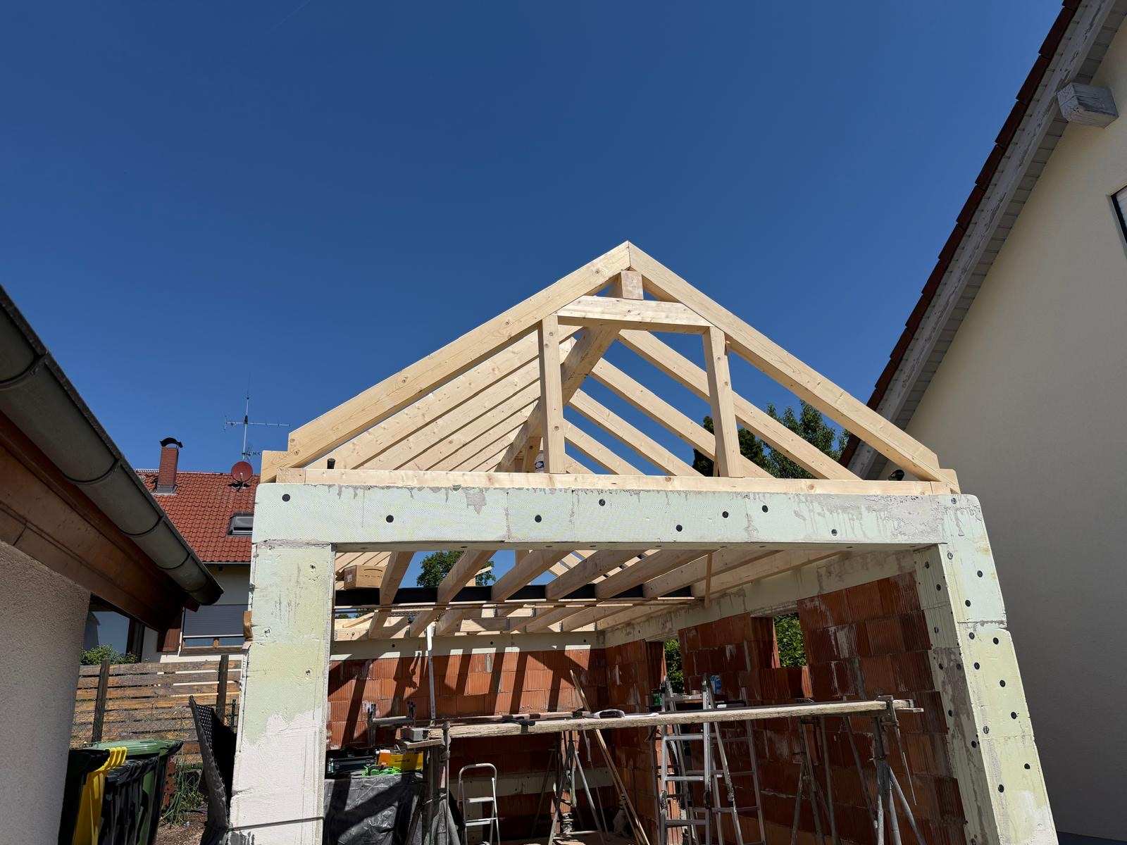 Holzdachstuhl einer Carport- oder Pergolakonstruktion im Rohbau vor klarem blauem Himmel